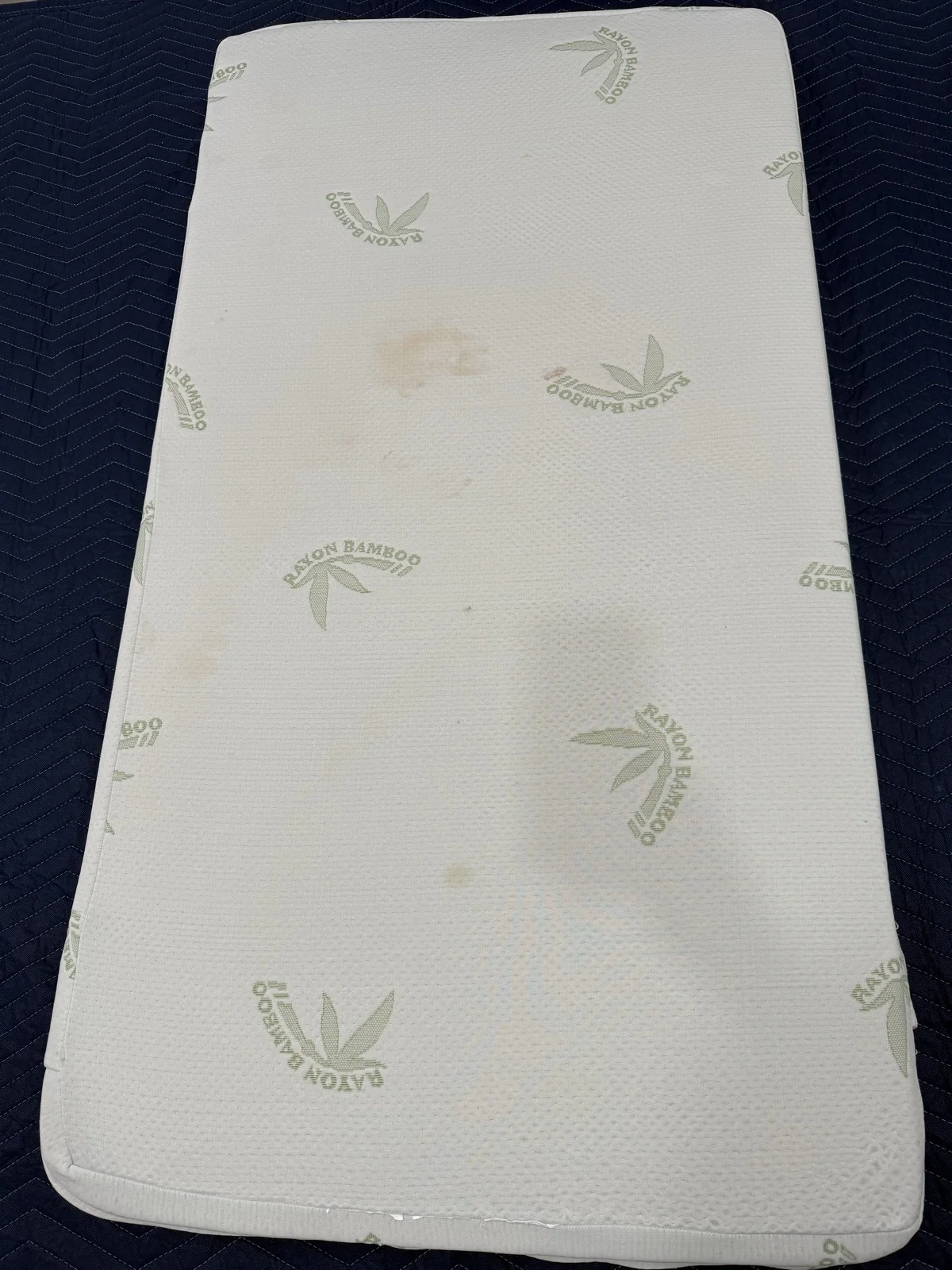Mattress before cleaning with visible marks on its white cover